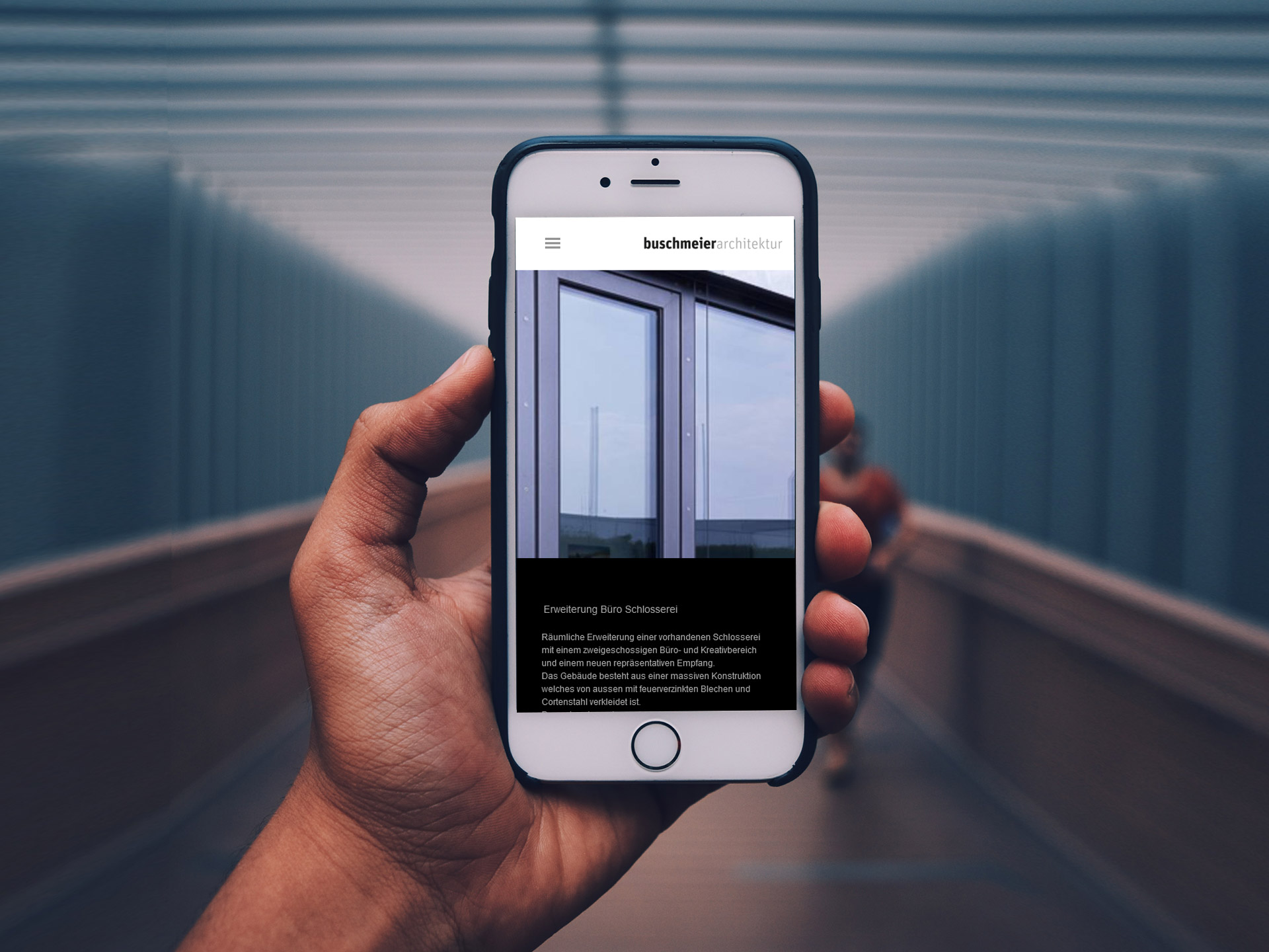 Hand hält Smartphone mit Architektur Webseite auf dem Bildschirm, im Hintergrund Brücke unscharf