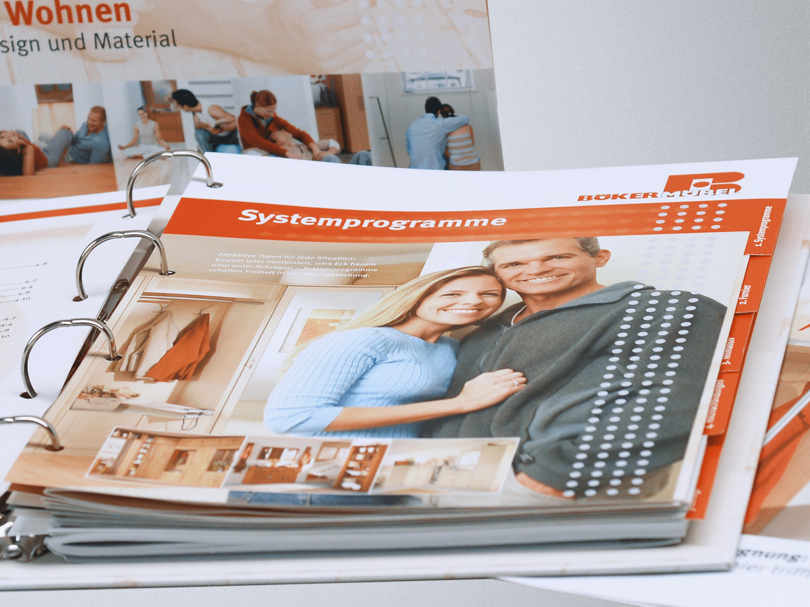 Links zwei zusammengefaltene Flyer und rechts ein ausgefalteter Flyer mit sichtbaren Knittfalten in Form eines Posters